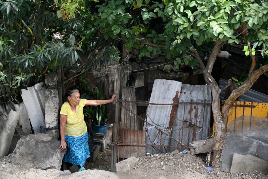 Una mujer se encuentra a la entrada de su casa en el barrio 14 de Enero en Tegucigalpa el 26 de noviembre de 2025. La vida de los hondureños refleja los dos flagelos que azotan al país: la violencia y la pobreza